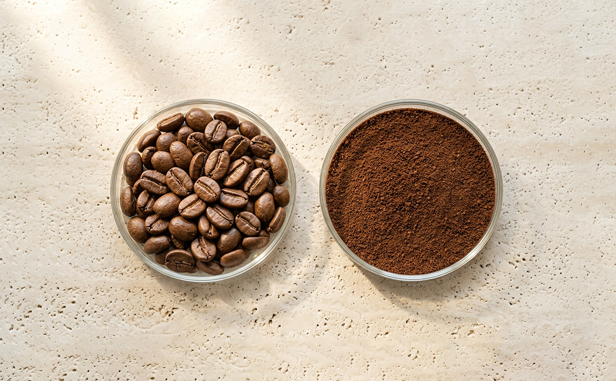 Whole coffee beans and ground coffee side by side in bowls